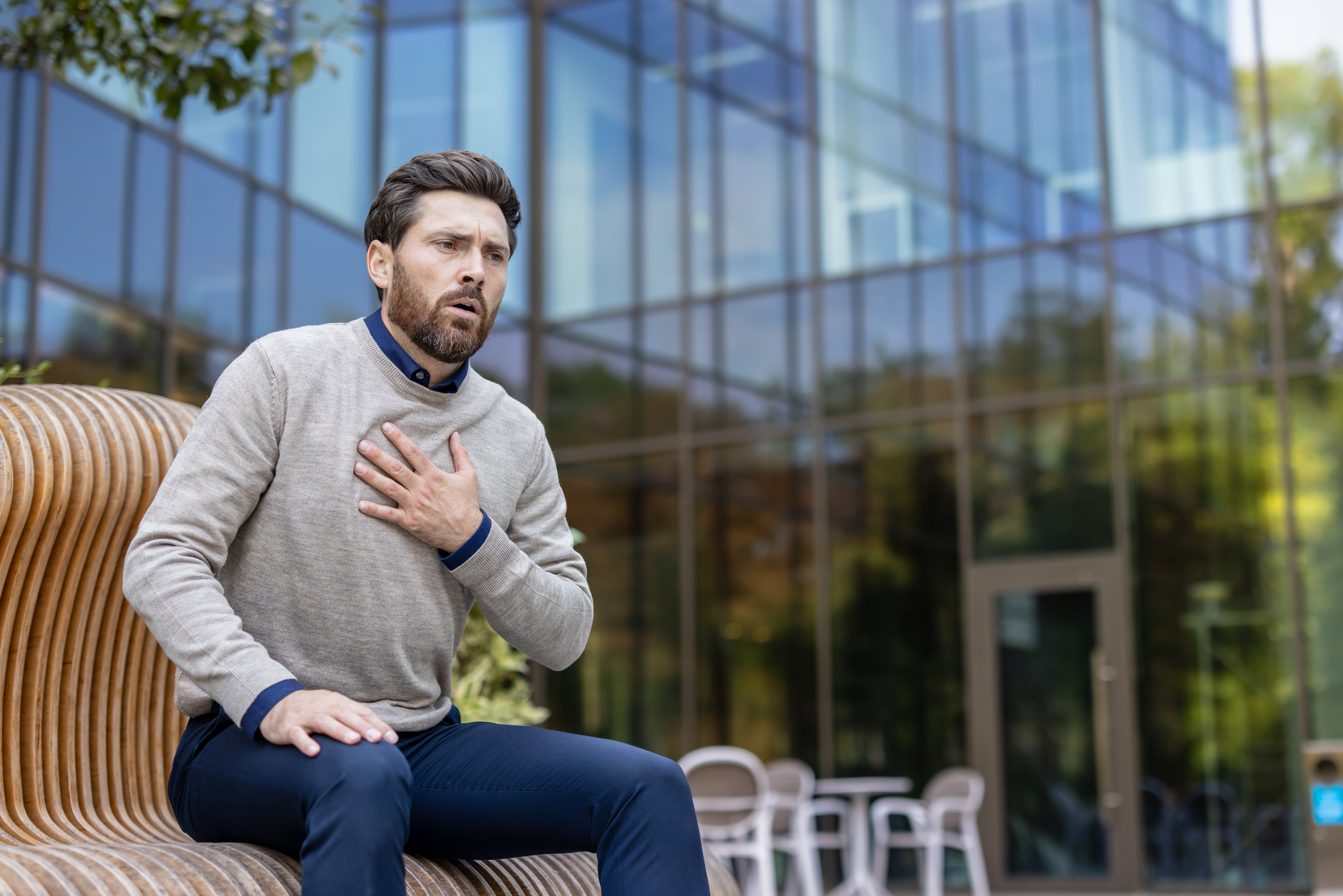 a man grabs his chest with his hand as he experiences heart attack symptoms like intense pressure and chest pain