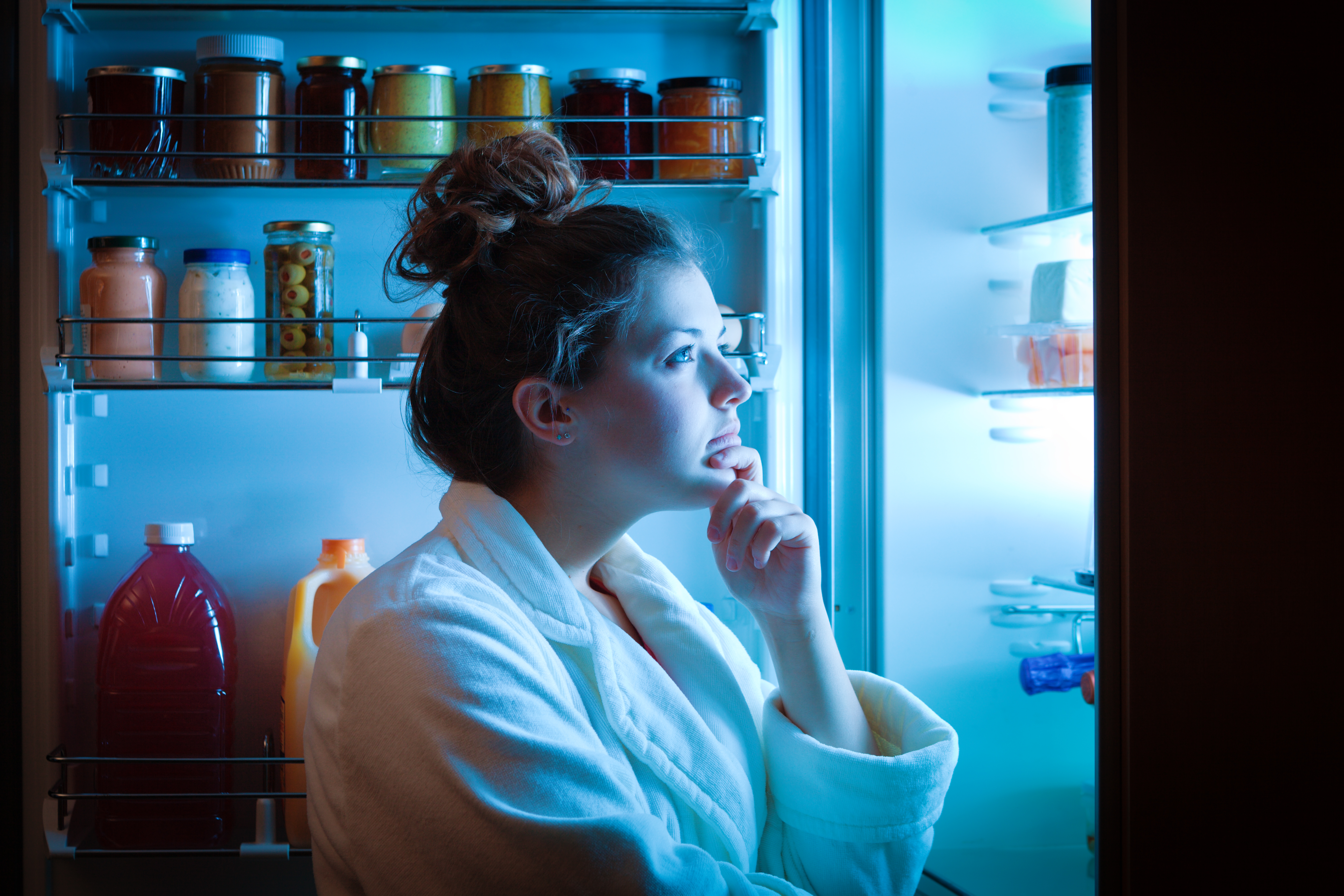a woman is shown looking in the fridge as she wonders what to eat