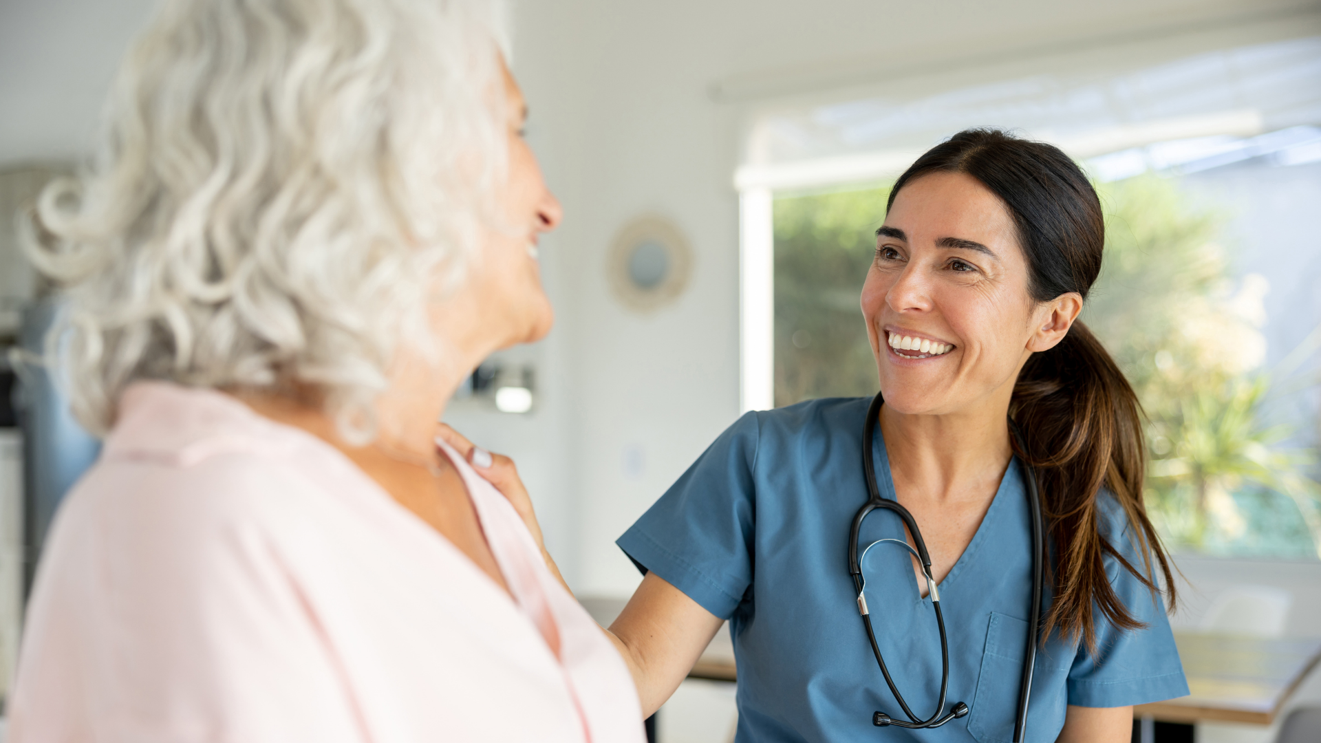 Happy doctor talking to a senior woman on a house call