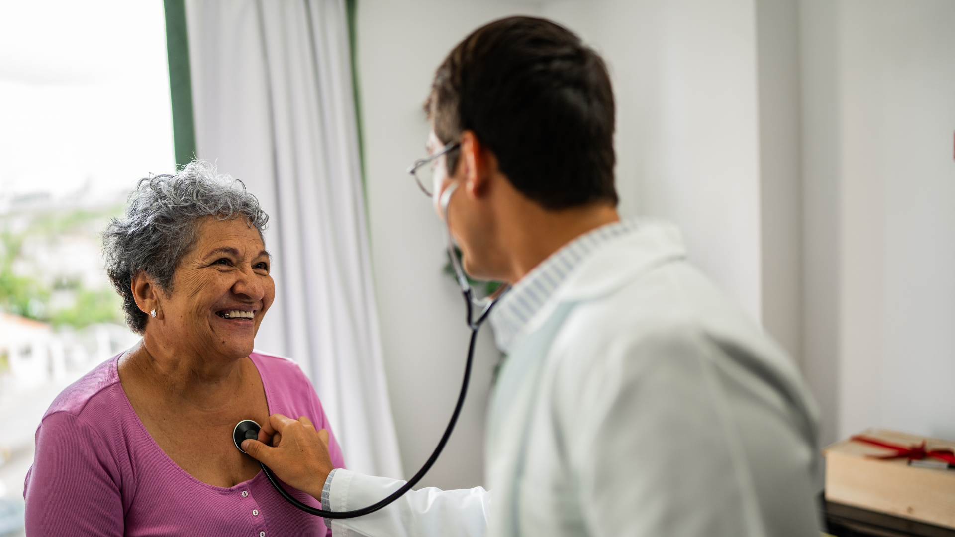 Doctor listening senior patient woman's heartbeat during consultation at hospital