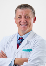 Austin Cantrell smiling and posing in a white coat