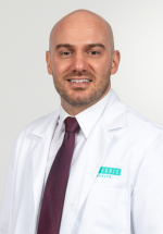 Cameron Ghafil smiling and posing in a white coat