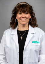 Deanna Sinclair smiling and posing in a white coat