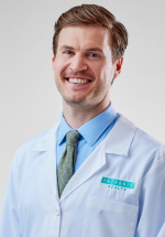 Evan Fene smiling in a white coat