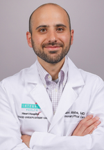 Isam Albaba smiling and posing in a white coat