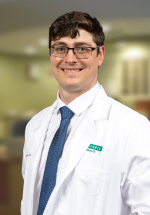 Mitchell Howe posing and smiling in a white coat