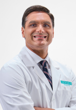 Sumit Walia smiling and posing in a white coat