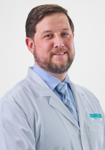 Trevor Logan smiling and posing in a white coat