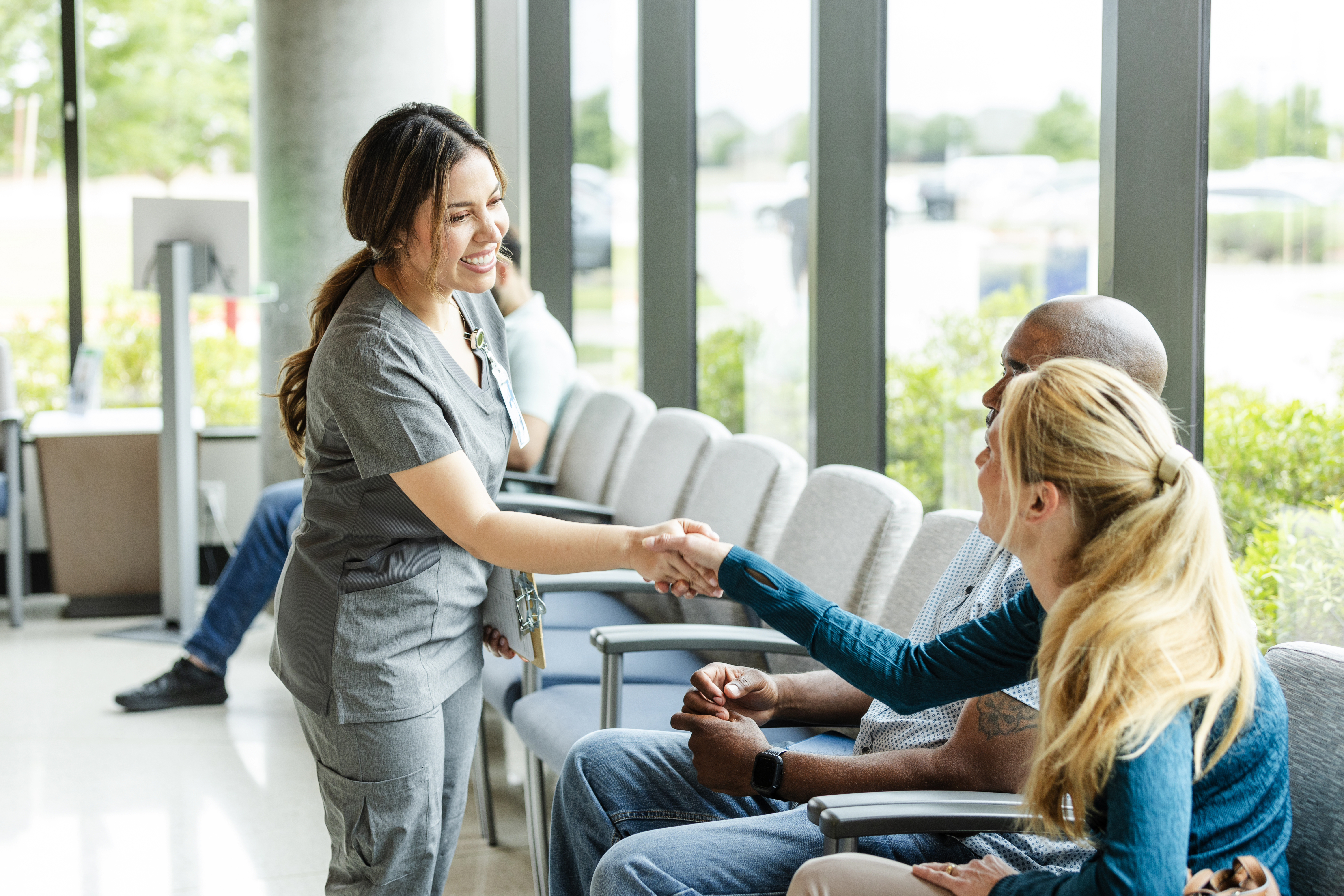 A nurse shaking a patients hand in the waiting room.