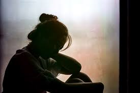Woman sitting in dark corner alone
