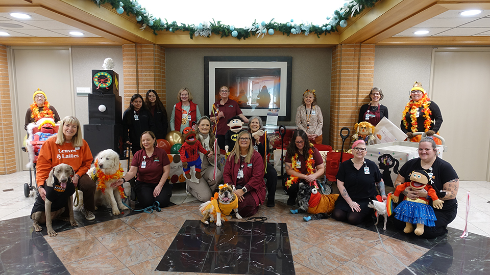 Caregivers stand with their Thanksgiving Day parade floats accompanied by INTEGRIS Health therapy dogs.