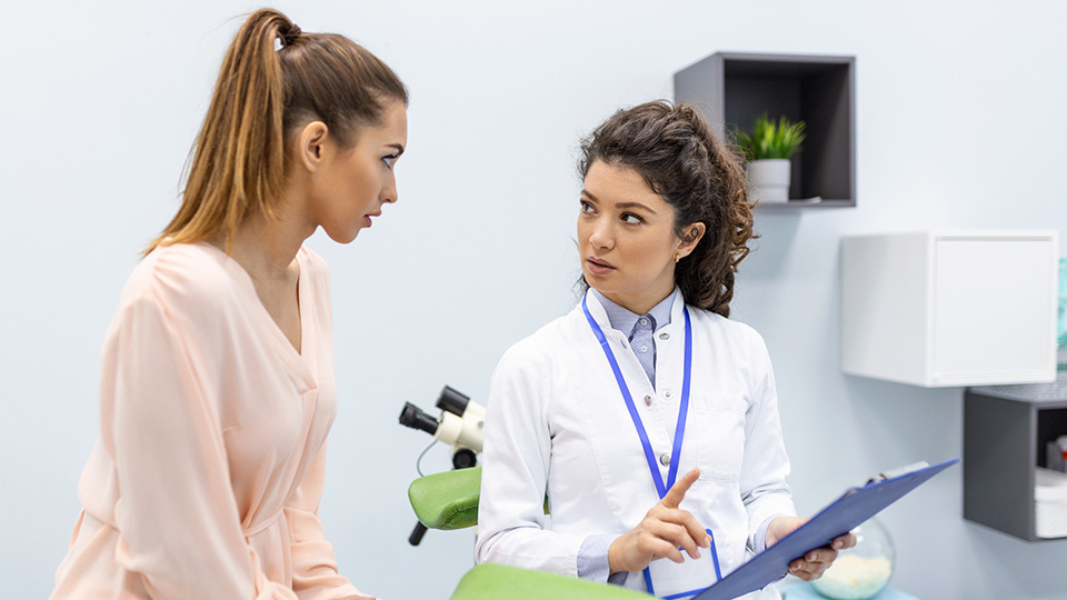Gynecologist talking with young female patient during medical consultation in modern clinic.
