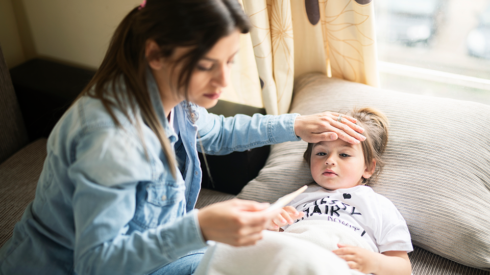 Mother checking on sick daughter lying in bed.