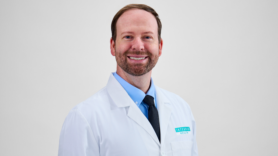 Adam Krouse posing and smiling in a white coat