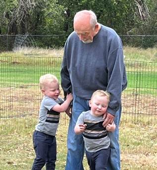 A senior man laughing with two toddlers