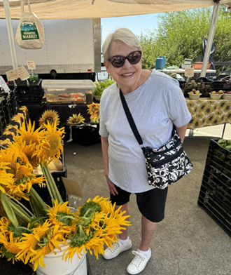 Kathy Allen smiling near yellow sun flowers