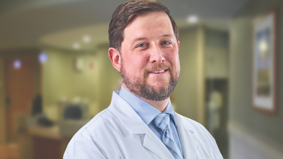 Trevor Logan smiling and posing in a white coat