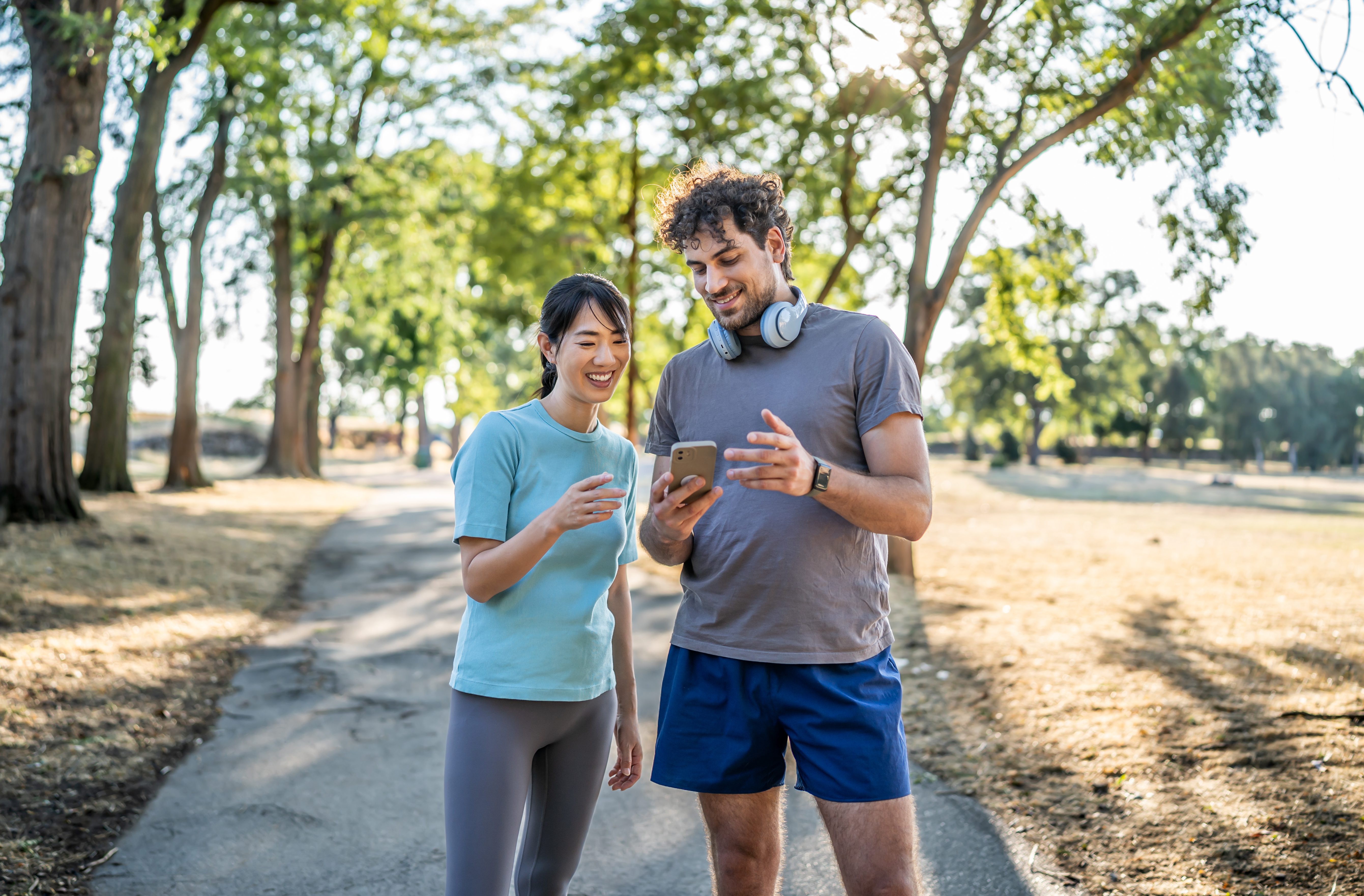 two people smiling at a phone while outside