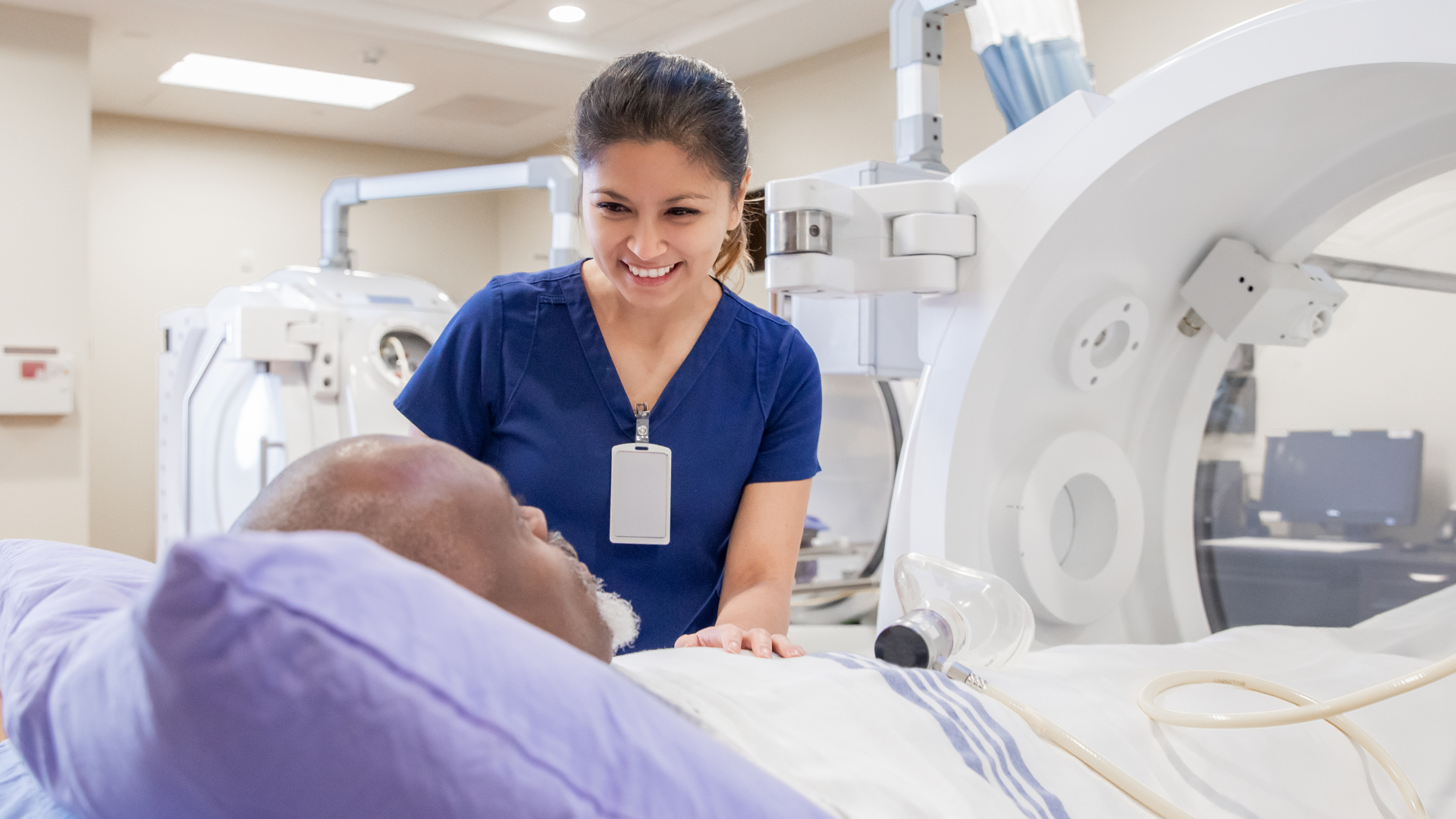 Female nurse prepares senior male for treatment in hyperbaric chamber