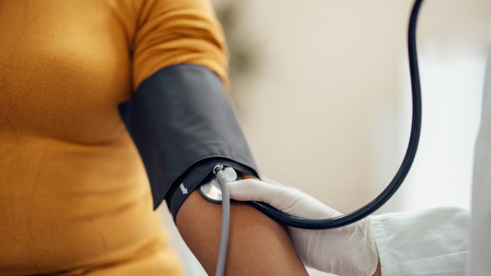 A doctor holding a stethoscope and a patient wearing a blood pressure cuff