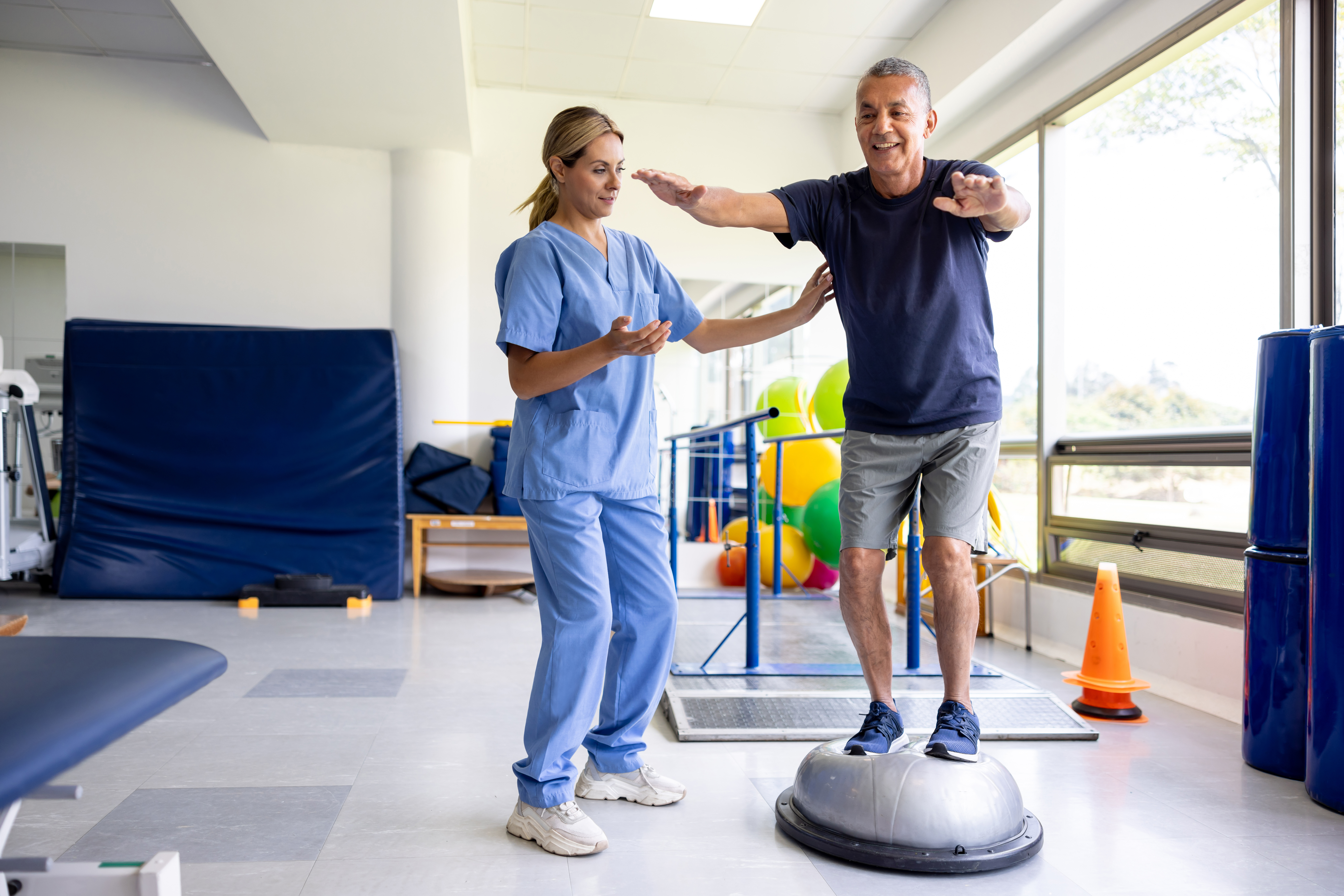A therapist helping a man balance with mobility exercises
