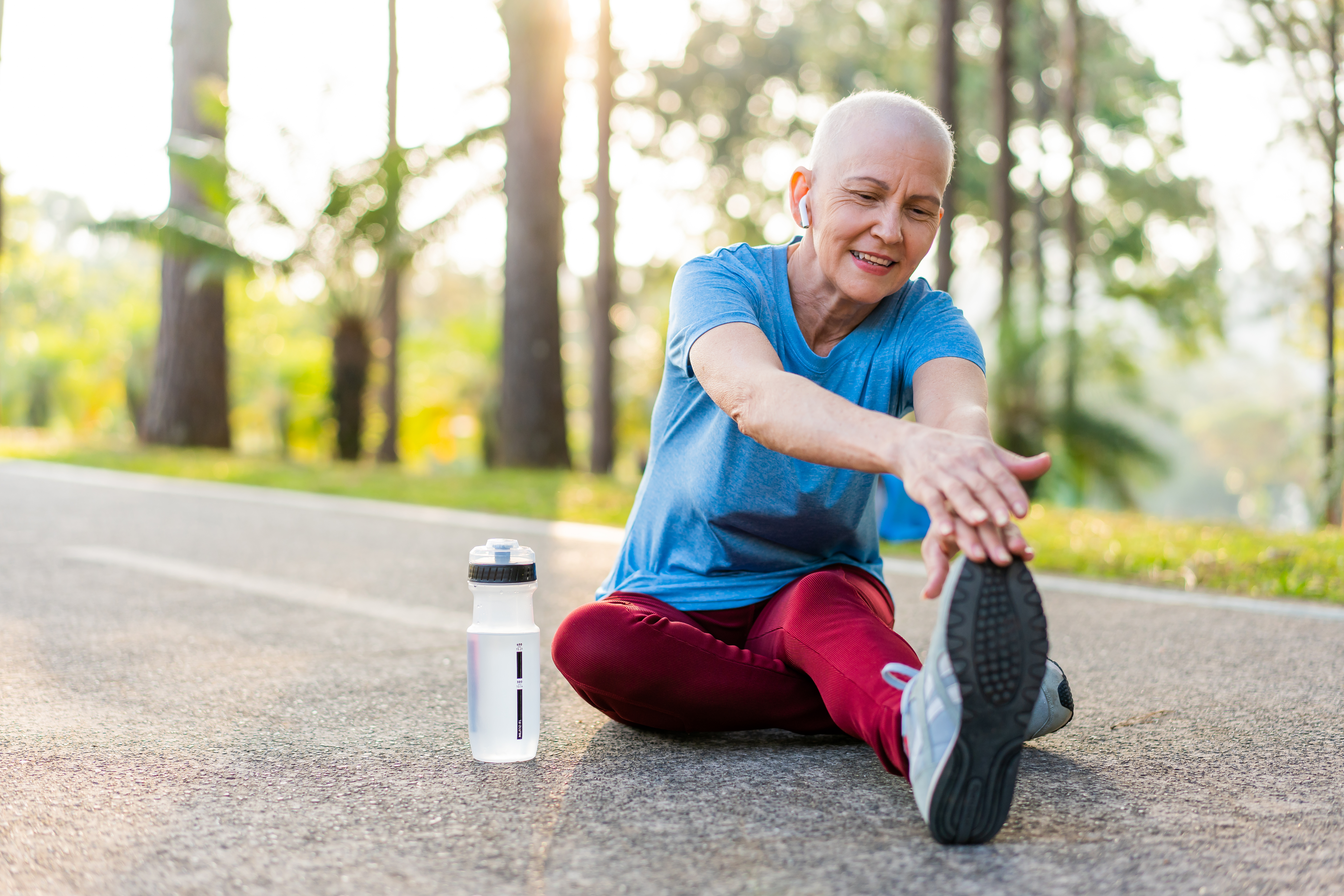 A woman stretching before a run with a water bottle beside her