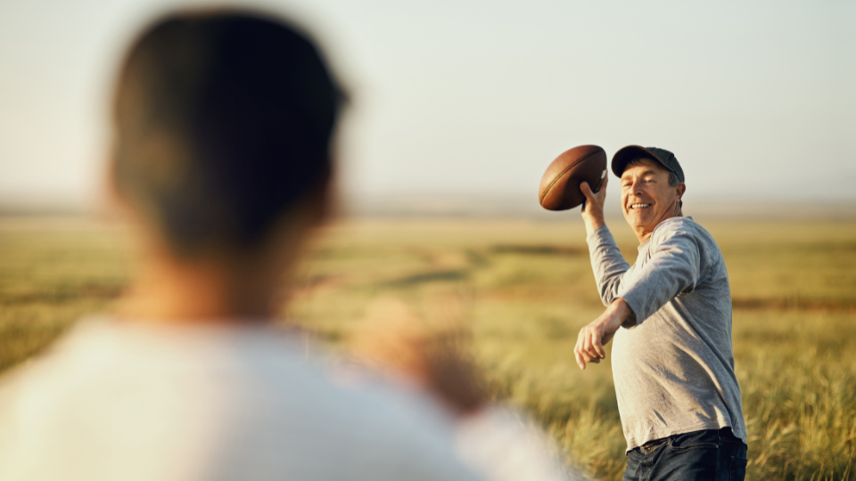Father tossing football to son in an open field
