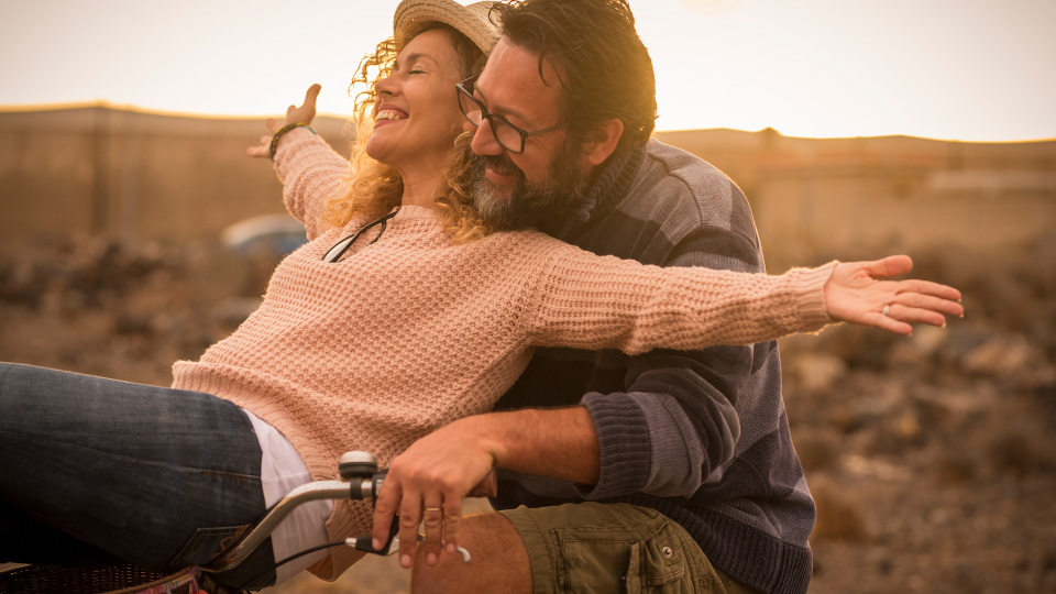 Happy adult people cheerful couple enjoy the outdoor leisure activity riding a bike together