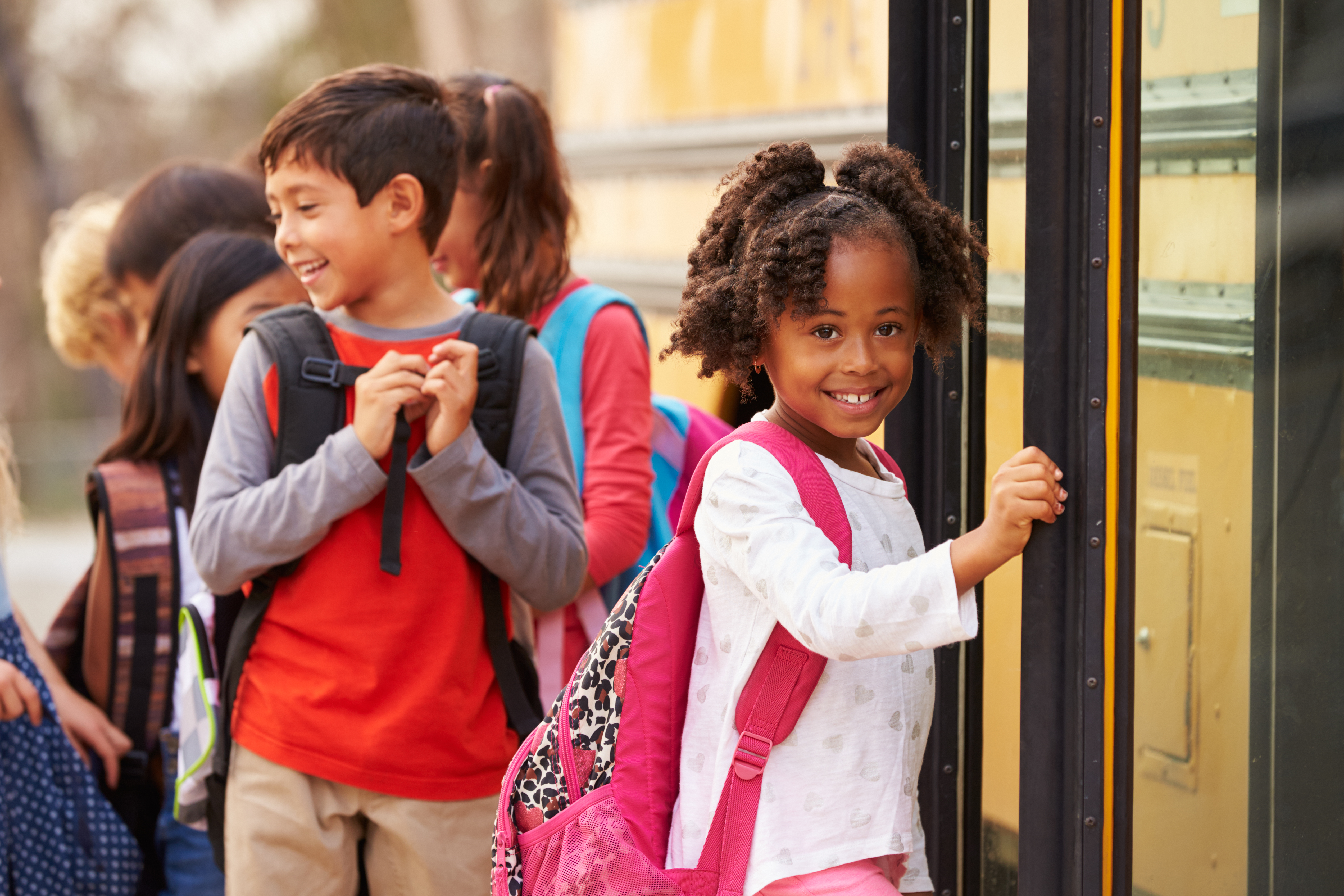 Elementary school girl at the front of the school bus line