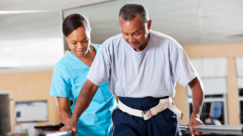Caregiver helping older patient with rehabilitation therapy