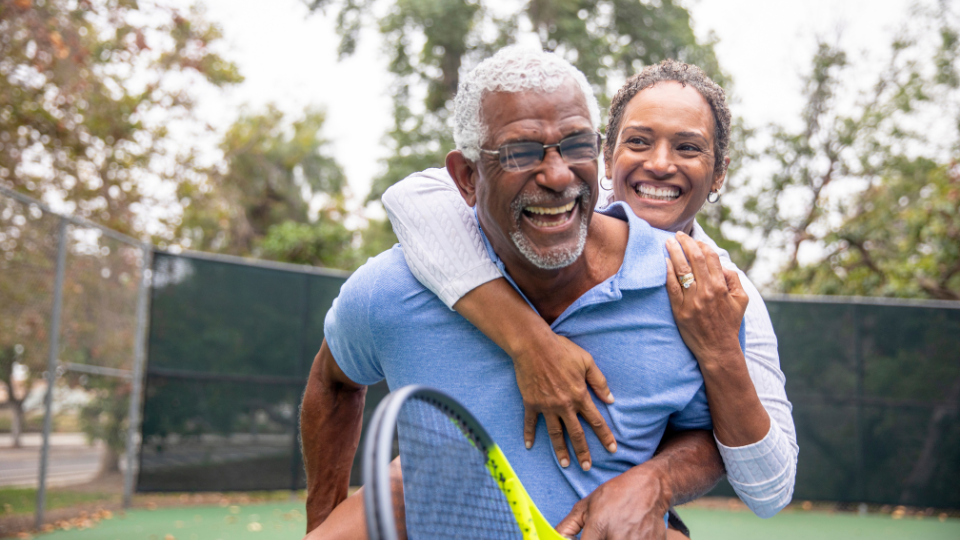 A smiling couple playing tennis on the court