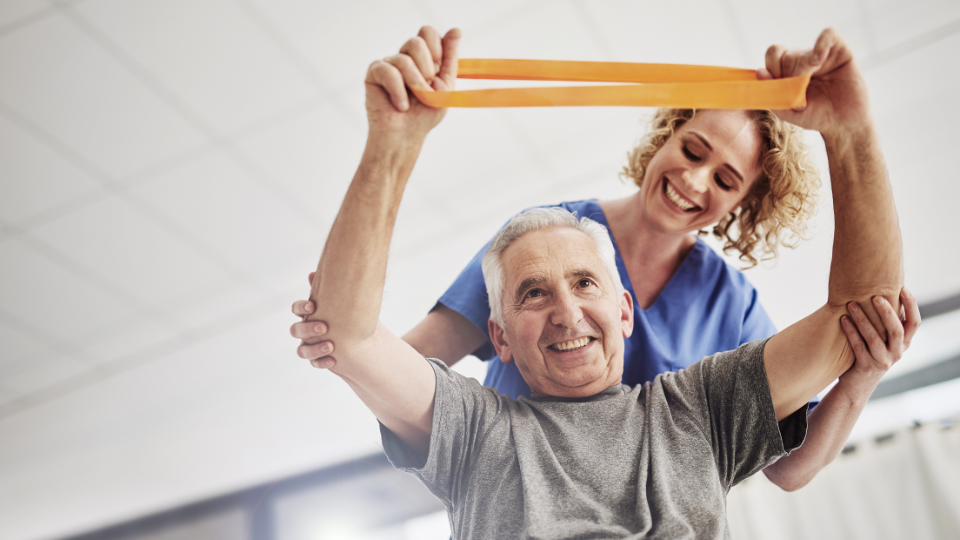 Physical therapist helping patient with arm stretches using a band