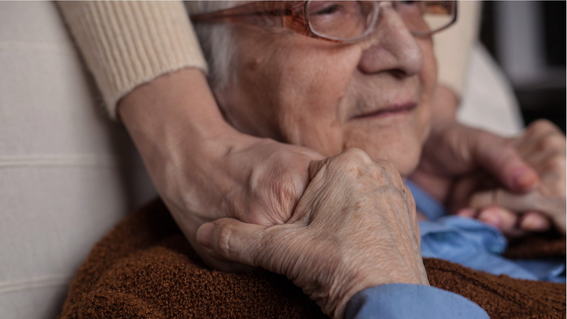 elderly woman holding hands with her caregiver