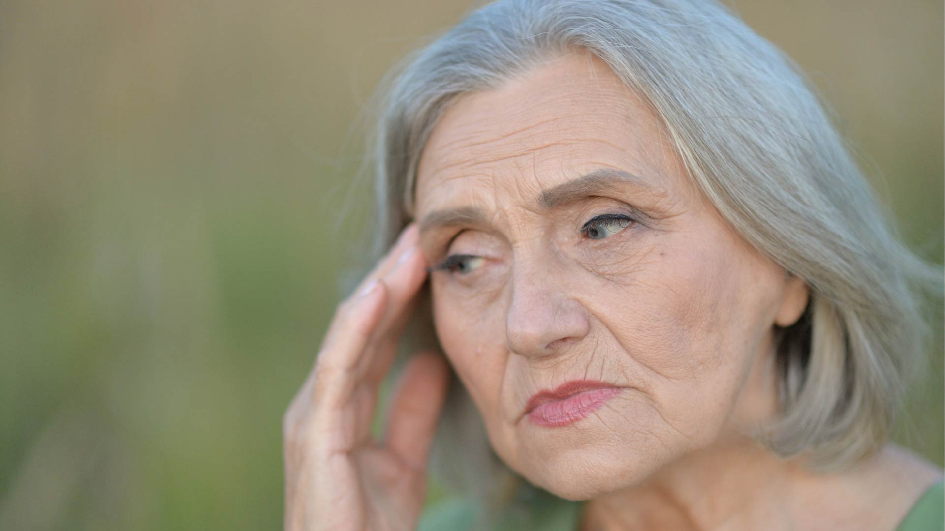 elderly woman touching her temple