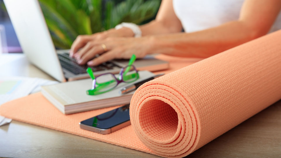 woman working on computer near yoga mat