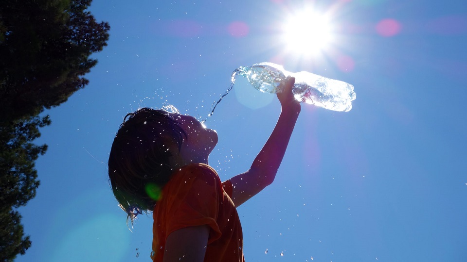 A child pouring water on their head in the summer heat.