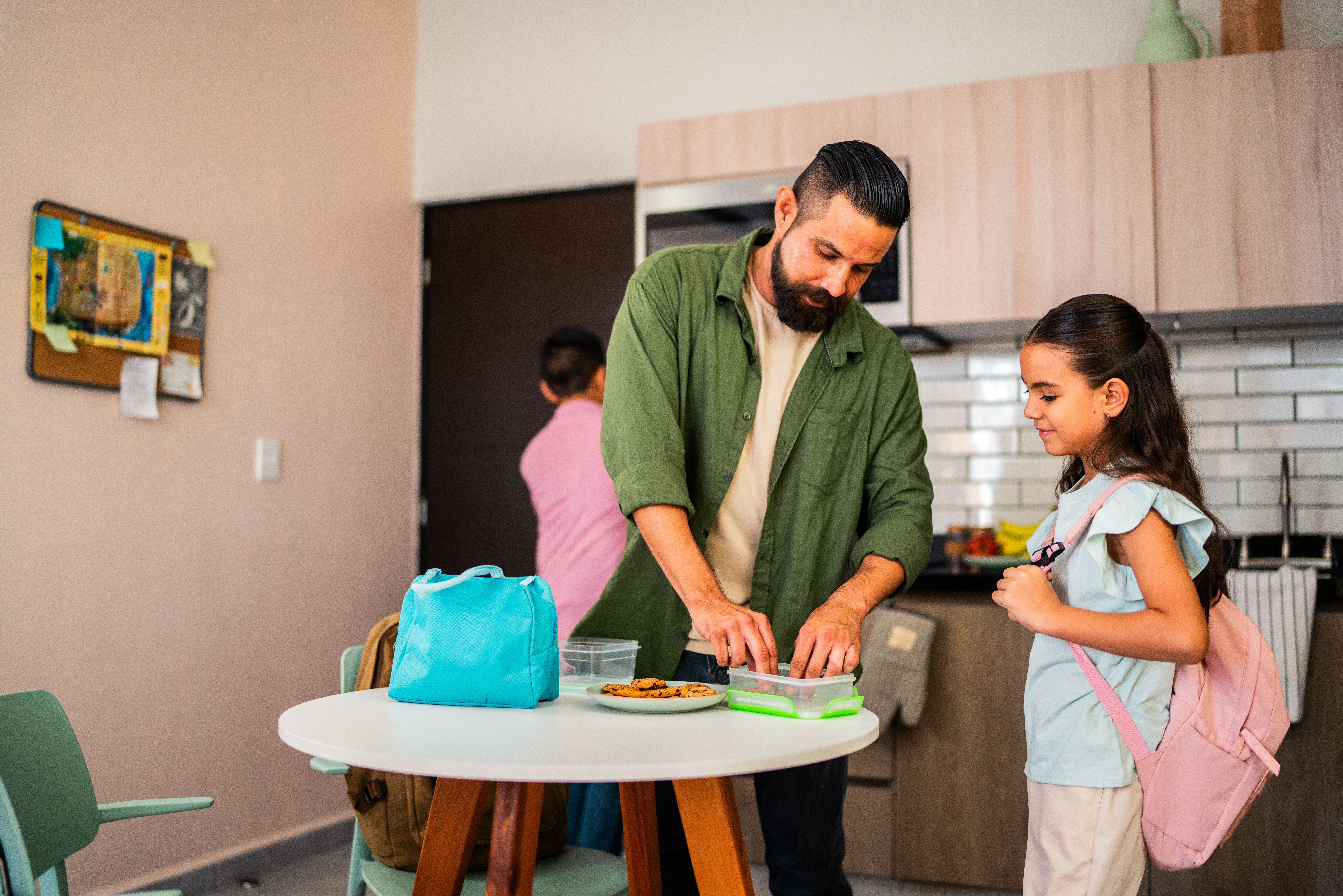 father helps his daughter pack lunch to bring to school