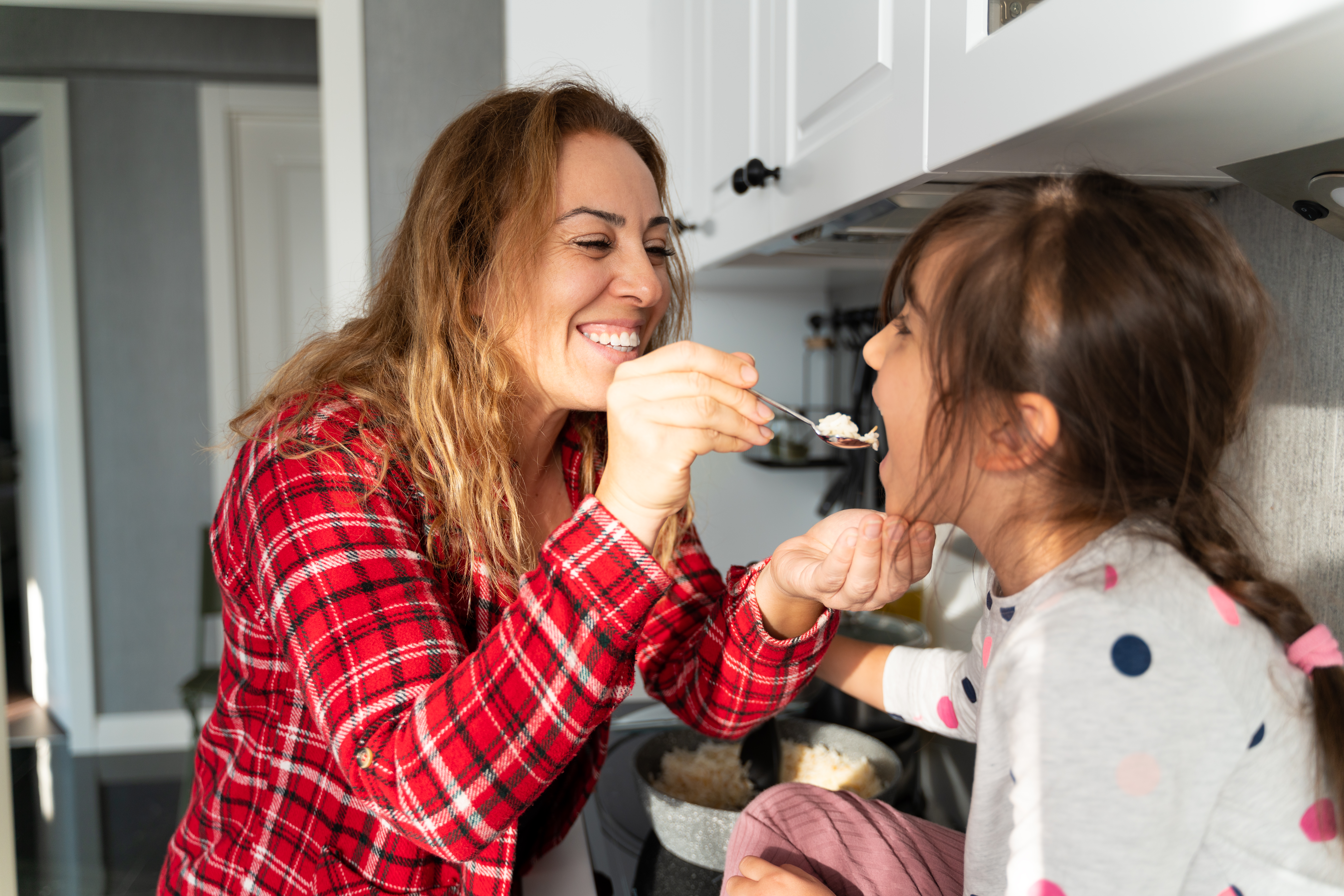 a mom feeds her daughter with a spoon
