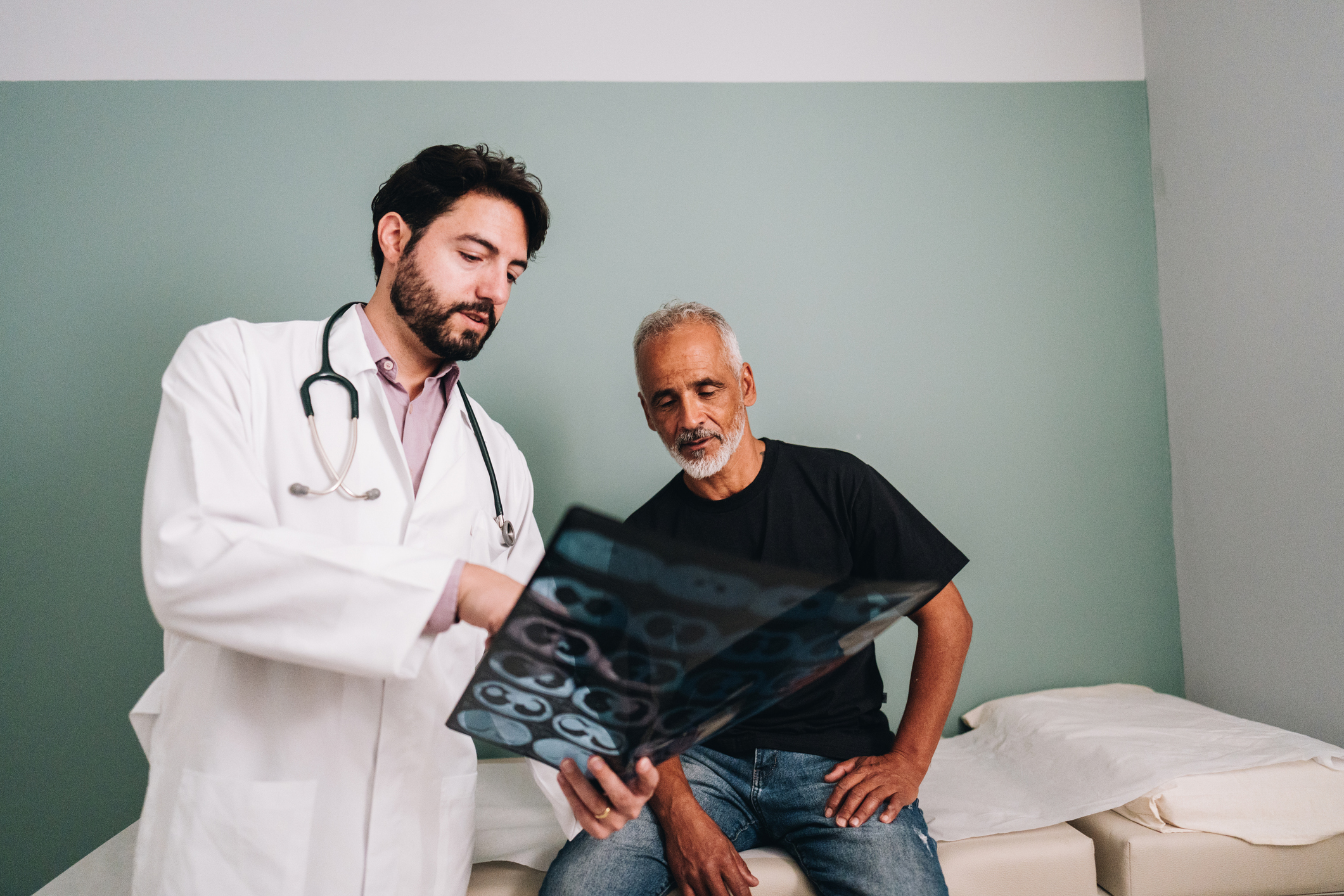 A doctor goes over an x-ray with an older male patient