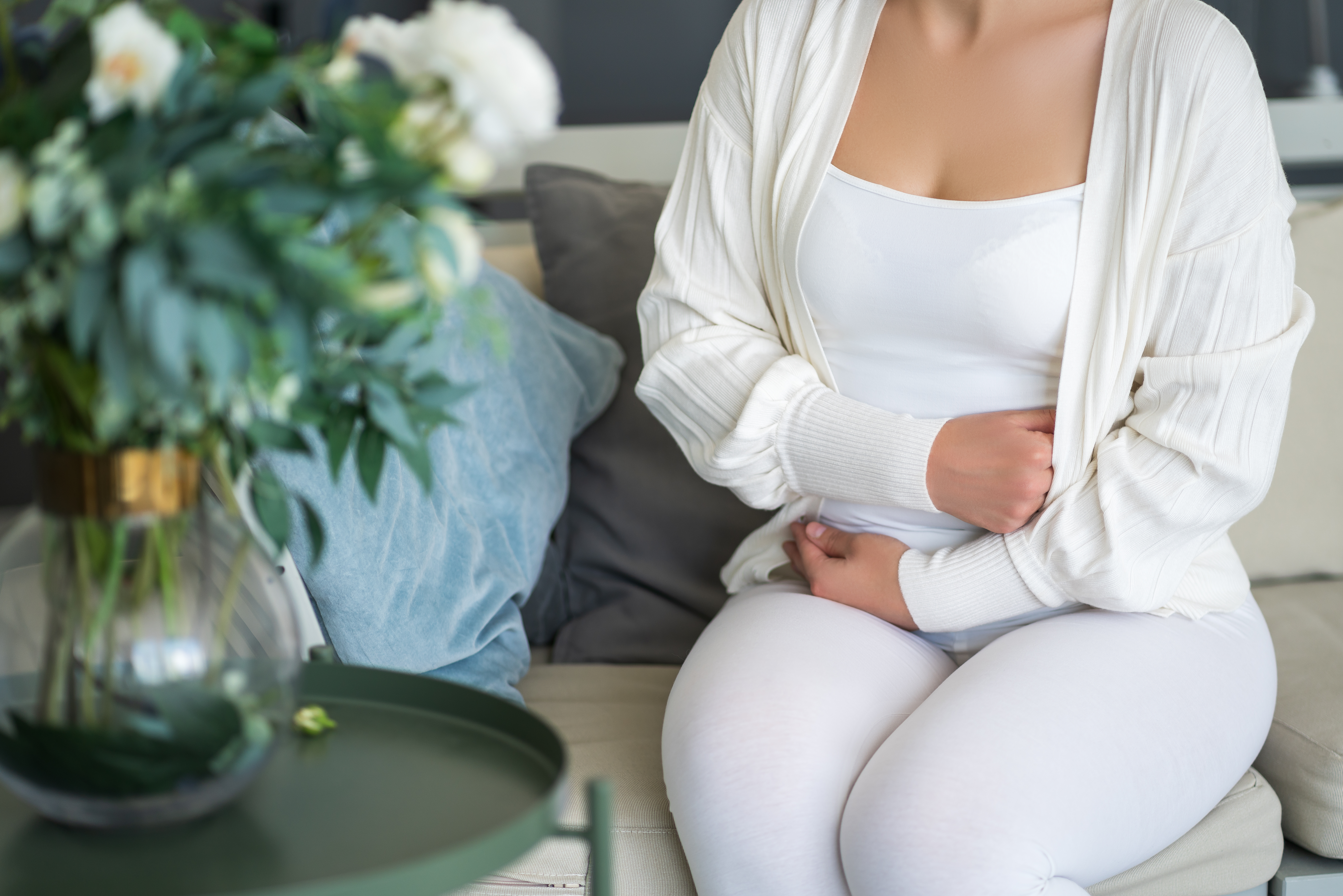 a woman sits uncomfortably at home