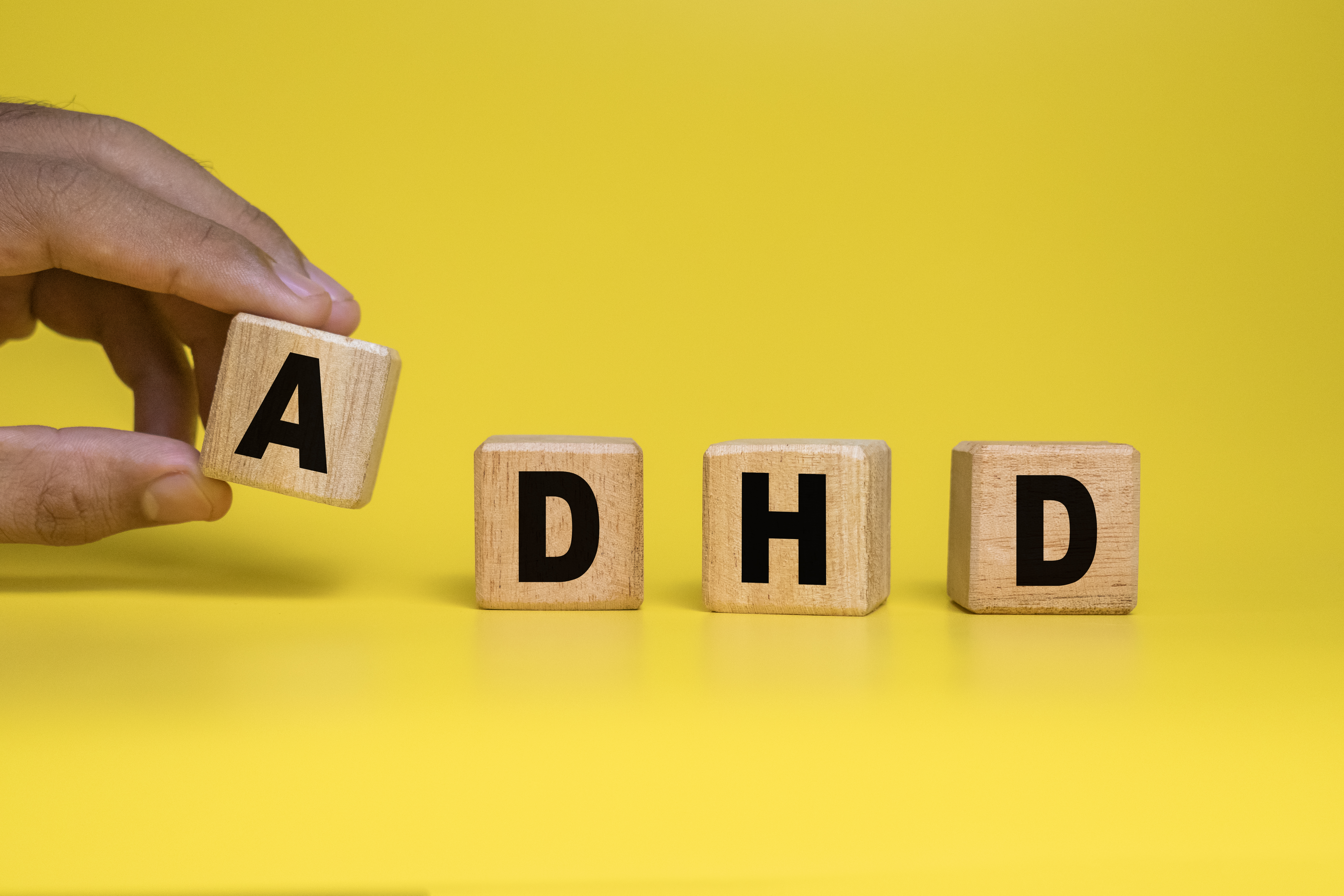 a hand is shown putting together wooden blocks that spell out ADHD