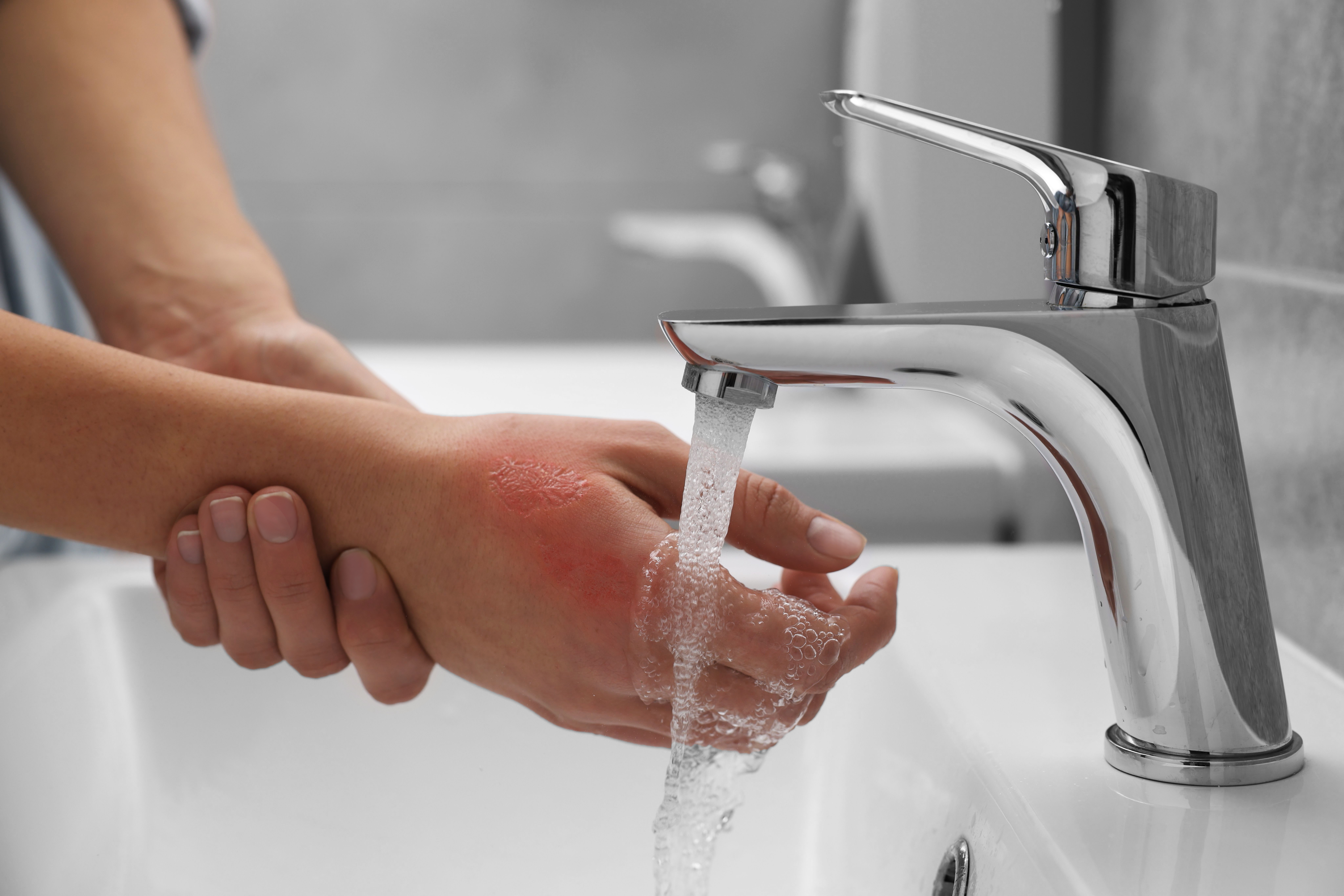 a person holds their hand under a running faucet