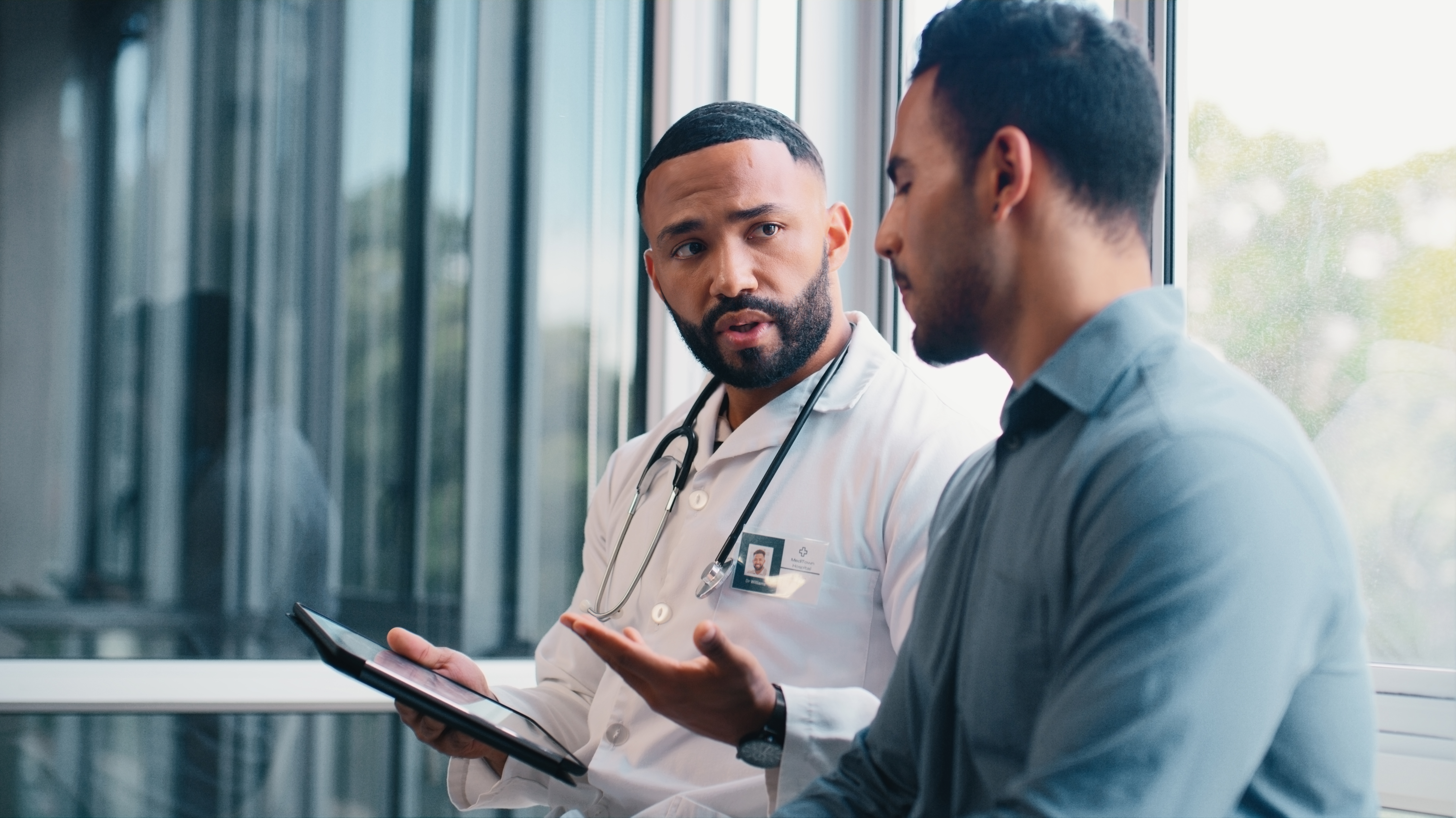 a doctor is shown talking with a patient as he explains test results from a monitor