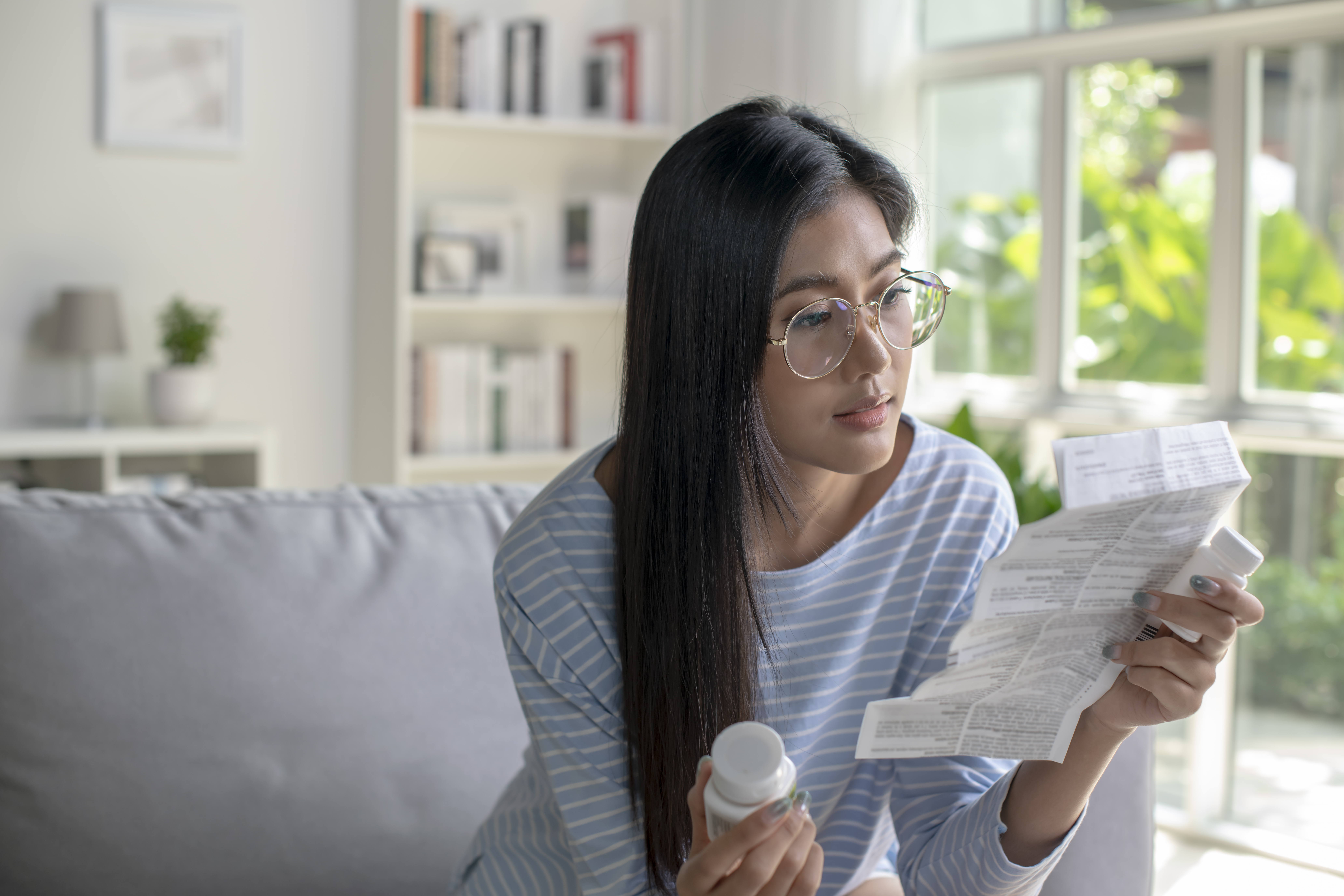 A woman is shown holding a prescription bottle and examining medical paperwork