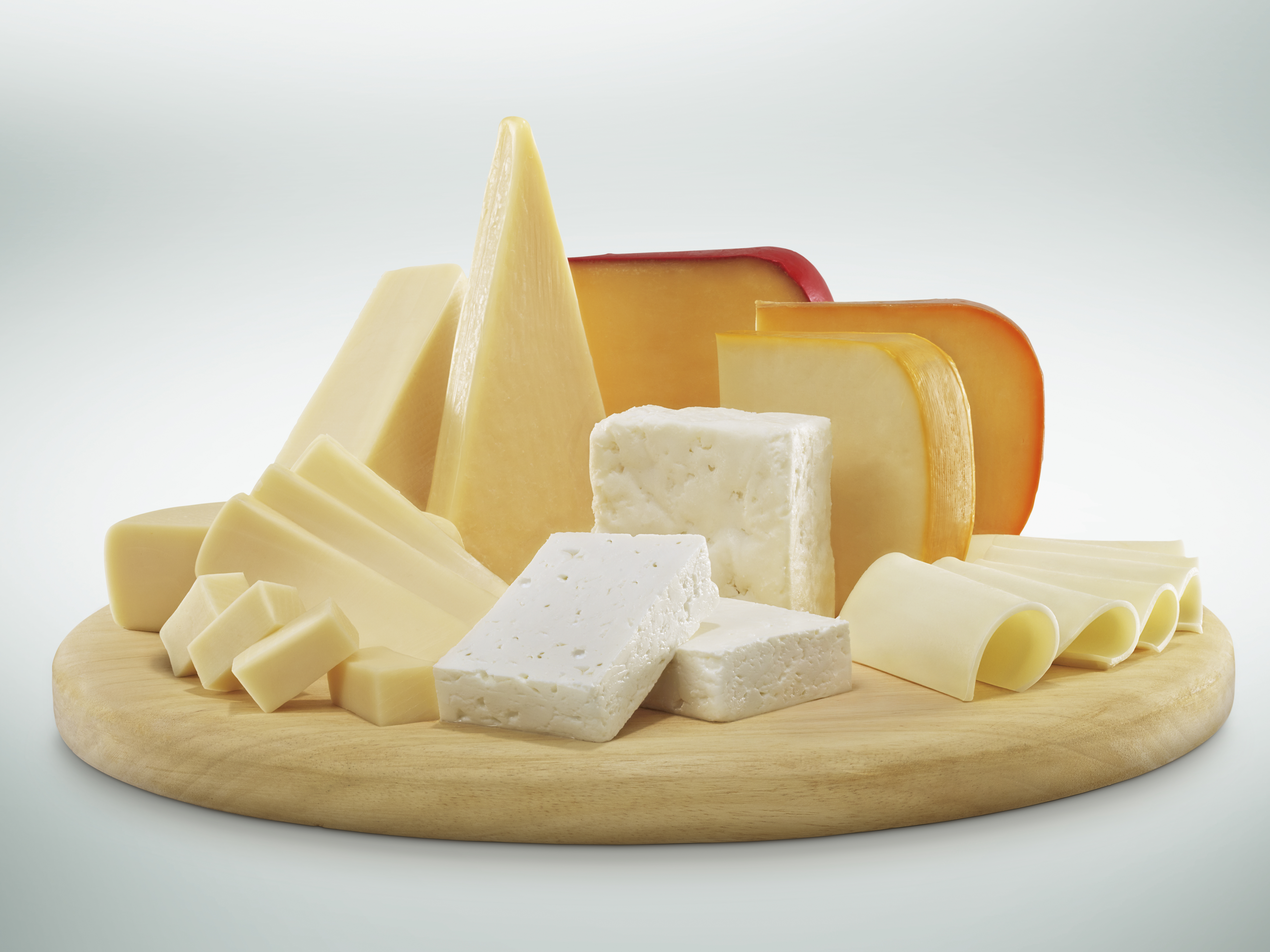a wooden serving tray with several different kinds of cheese