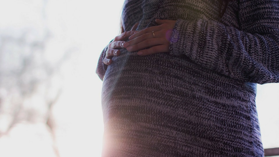 pregnant woman resting hands on baby bump