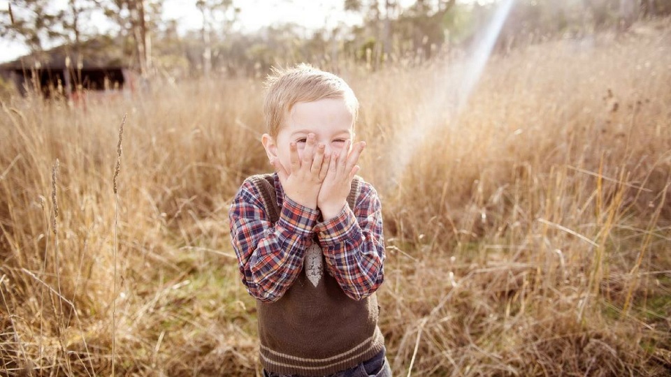 young boy standing in a field of wheat