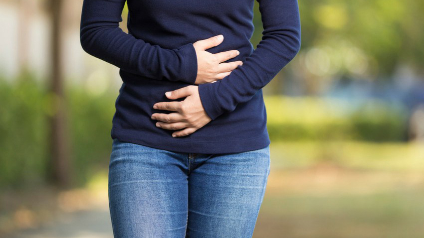 woman in blue sweater clutching her stomach