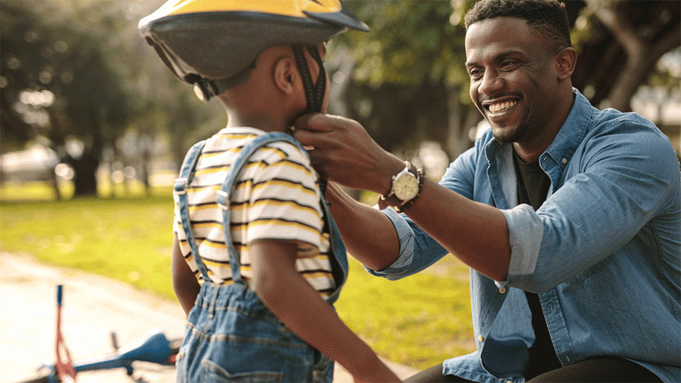 father teaching child how to ride bike