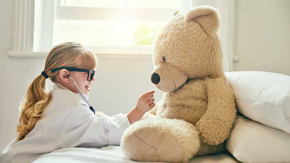 Child checking bear with stethoscope